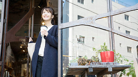 コーヒーをテイクアウトして店を出る女性の風景
